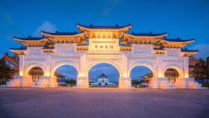The illuminated grand gate of Chiang Kai-shek Memorial Hall with intricate designs and a clear blue evening sky