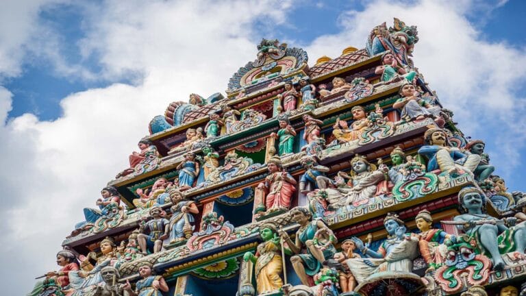 Intricate sculptures and vibrant colors adorn the Sri Veeramakaliamman Temple in Little India, Singapore, under a bright blue sky.