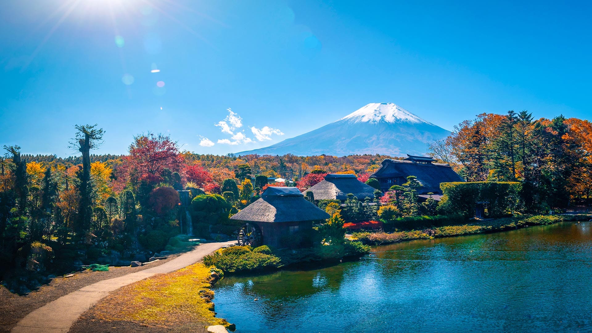 Traditional thatched-roof houses with Mount Fuji in the background and a serene lake in Oshino Hakkai