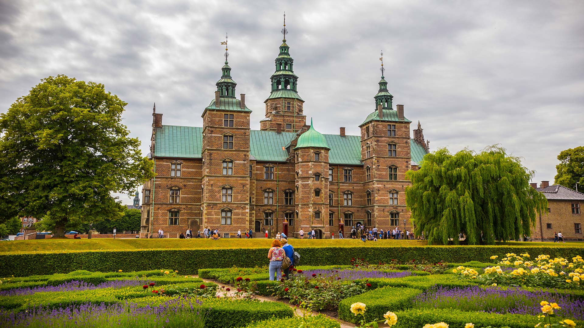 Rosenborg Castle with lush green gardens and visitors, located in Copenhagen, Denmark.