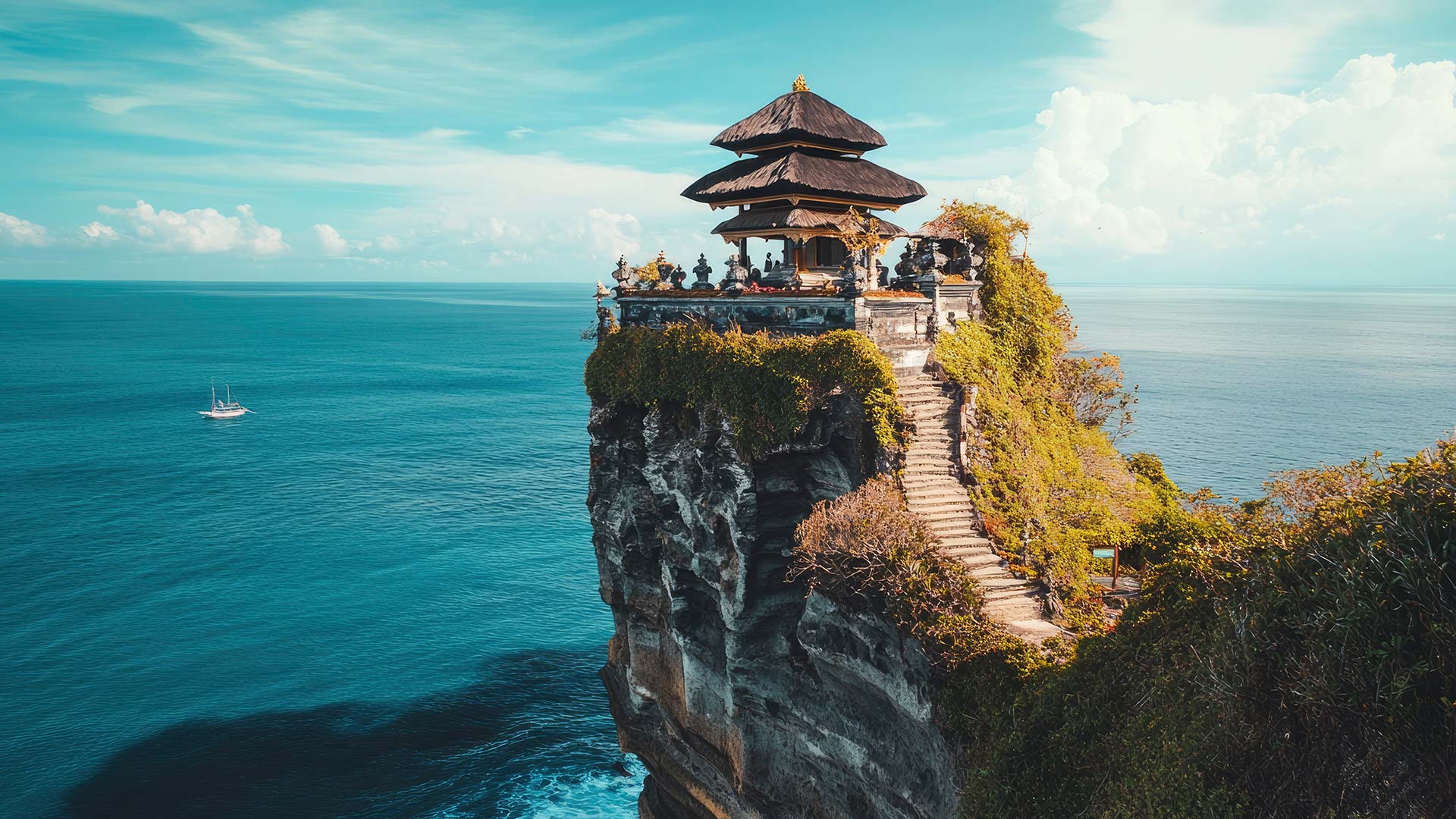 The iconic Uluwatu Temple perched dramatically on a cliff, overlooking the endless blue expanse of the Indian Ocean.