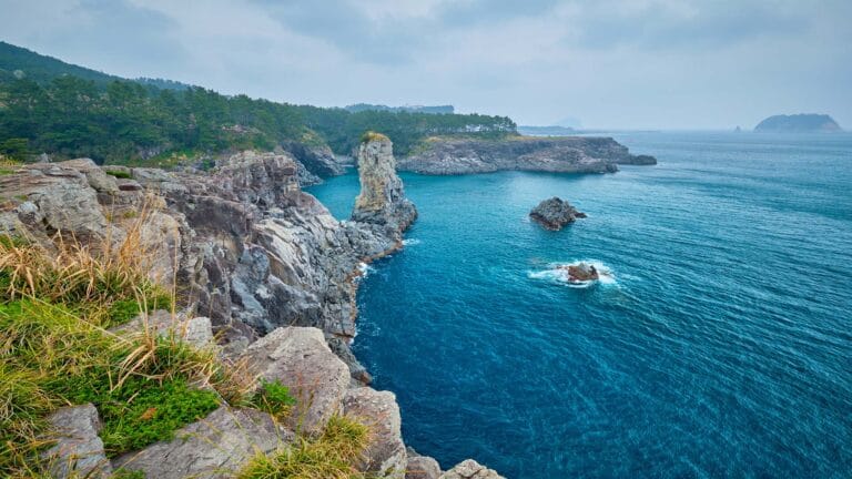 Dramatic coastline with jagged cliffs and turquoise waters at Jeju Island, South Korea.